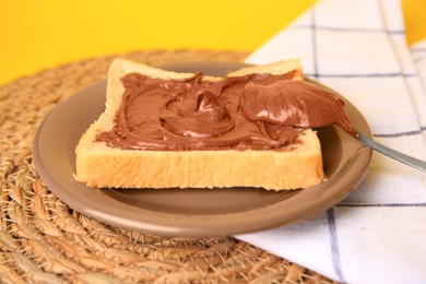 Photo of Tasty toast with chocolate paste and napkin on wicker mat, closeup