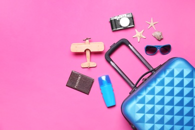 Photo of Flat lay composition with suitcase and beach objects on pink background. Space for text