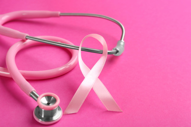 Photo of Pink ribbon and stethoscope on color background, closeup. Breast cancer concept