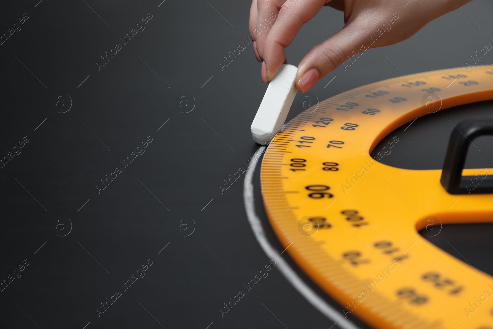 Photo of Woman drawing with chalk and protractor on blackboard, closeup. Space for text