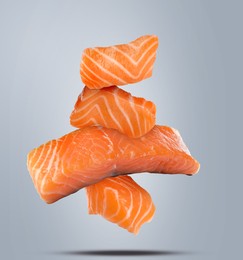 Cut fresh salmon falling on light grey background