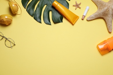 Photo of Flat lay composition with sun protection products and summer items on yellow background. Space for text