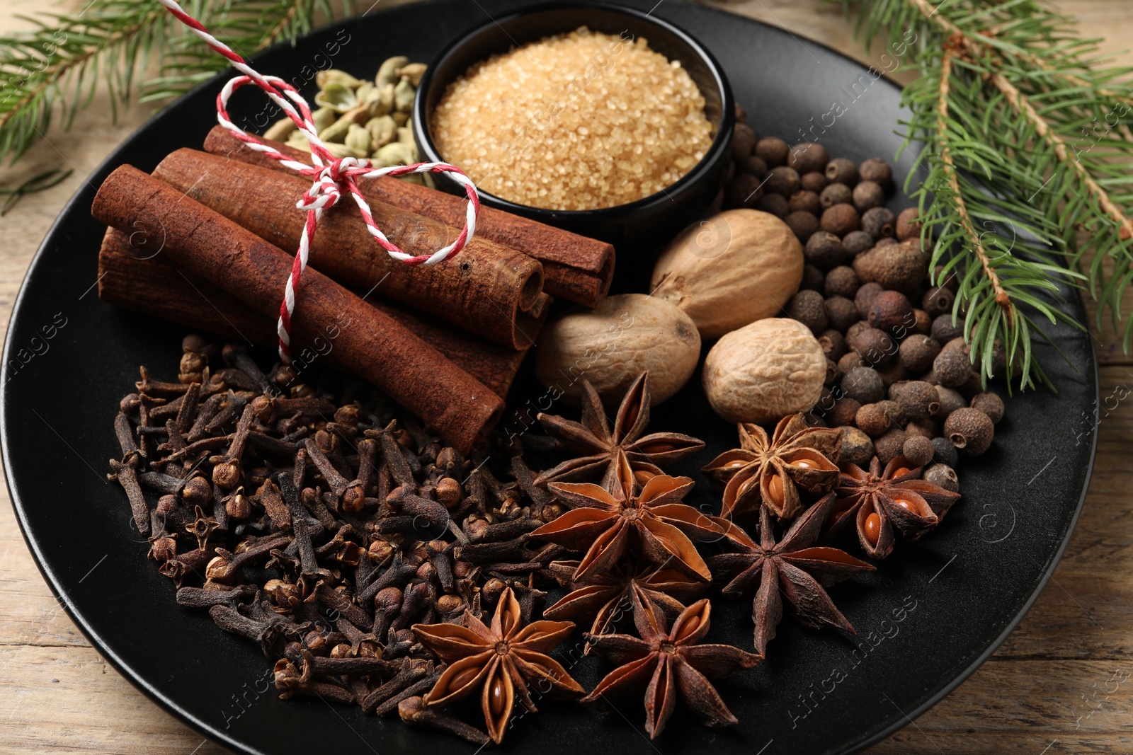 Photo of Dishware with different spices and fir branches on table, closeup