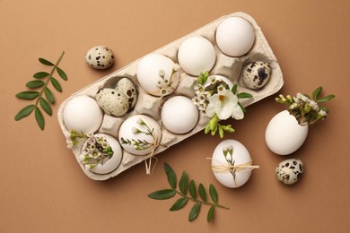 Festive composition with eggs and floral decor on brown background, flat lay. Happy Easter