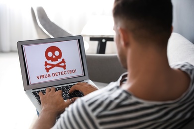 Photo of Man using laptop with warning about virus attack at home