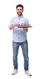 Smiling man holding chessboard with game pieces on white background