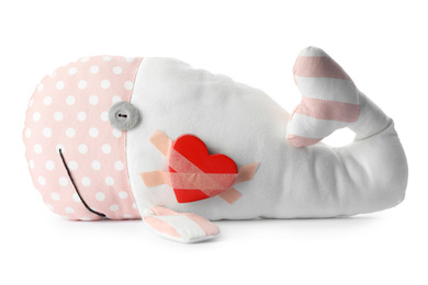 Toy whale with red heart attached by sticking plasters isolated on white
