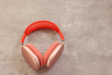 Photo of Stylish pink headphones on light grey table, above view. Space for text