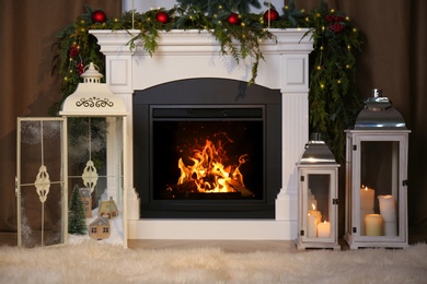 Photo of Beautiful Christmas lanterns near fireplace in room with festive decor