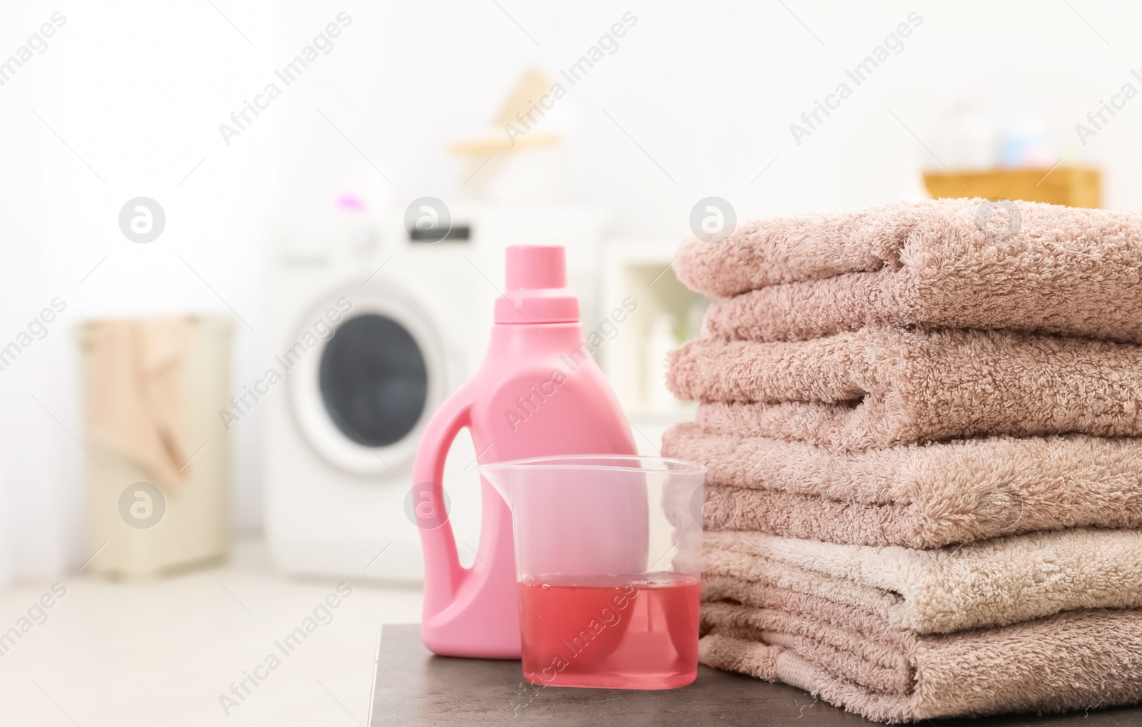 Photo of Stack of clean towels and liquid detergent on table in bathroom. Space for text