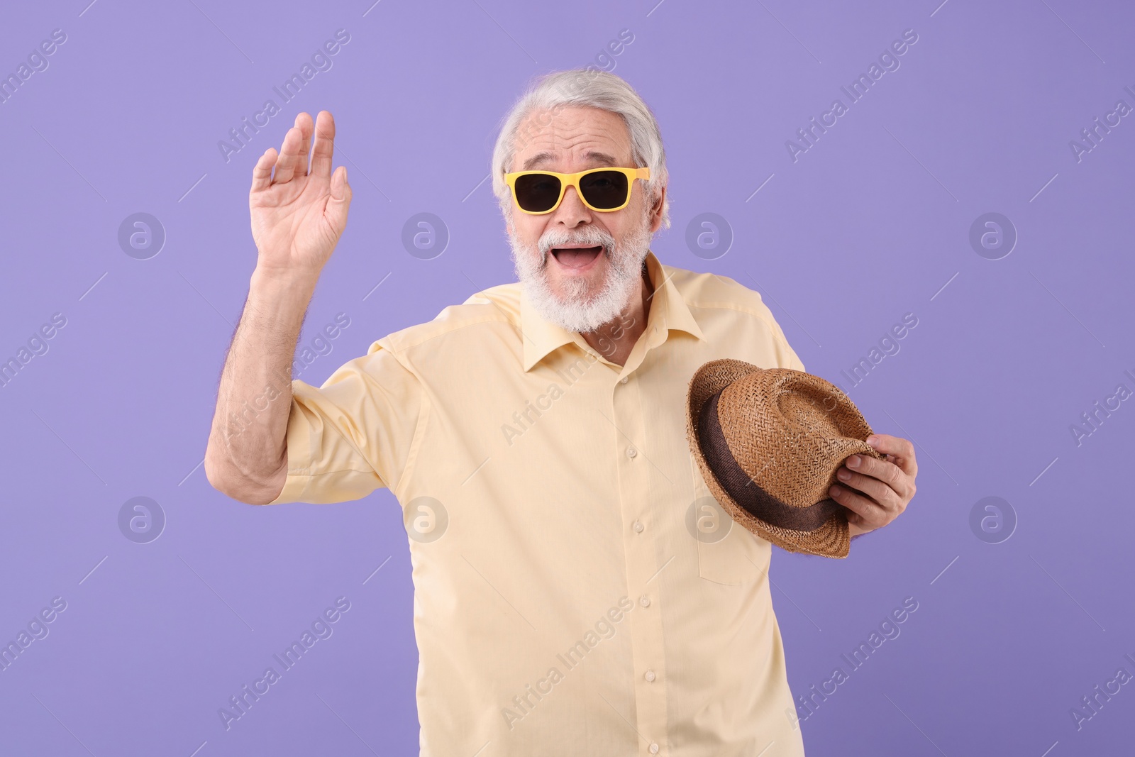 Photo of Portrait of stylish grandpa with sunglasses and hat on purple background