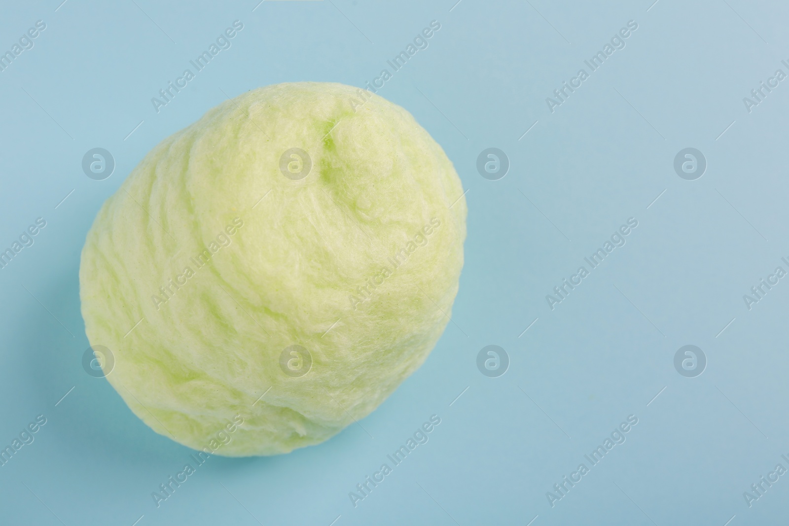 Photo of Sweet cotton candy on light blue background, space for text