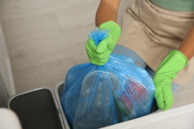 Photo of Woman taking garbage bag out of bin at home, closeup