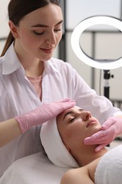 Photo of Cosmetologist making face massage to client in clinic