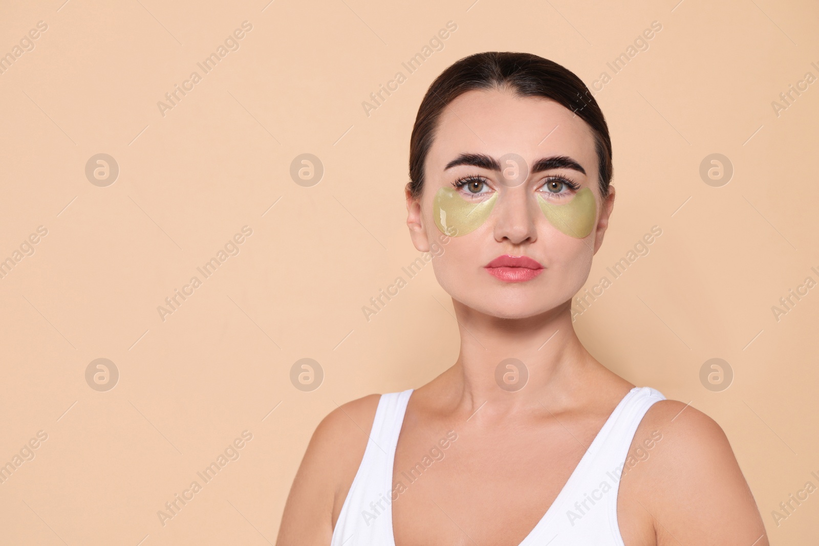 Photo of Beautiful woman with under eye patches on beige background. Space for text