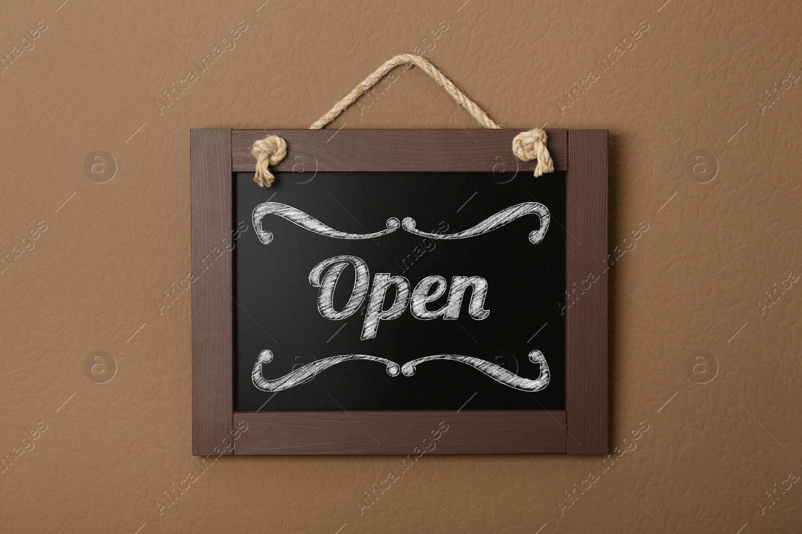 Image of Small chalk board with word Open on brown wall