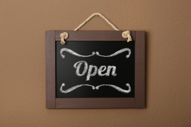 Small chalk board with word Open on brown wall