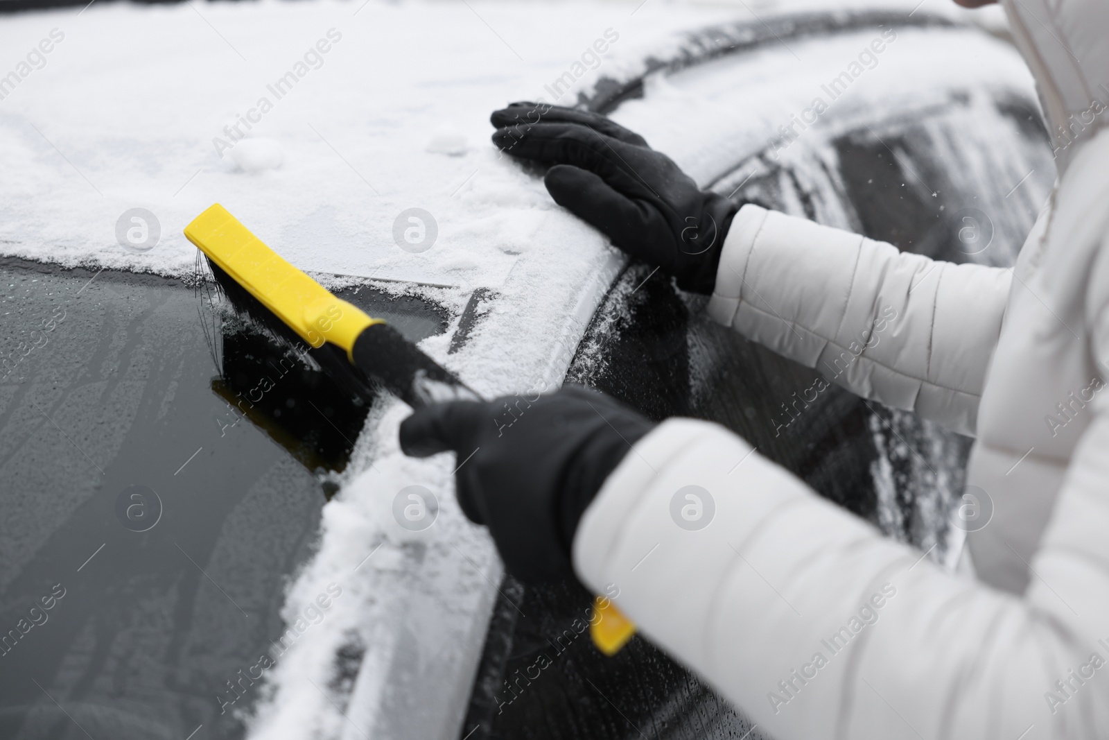 Photo of Man cleaning snow from car windshield outdoors, closeup