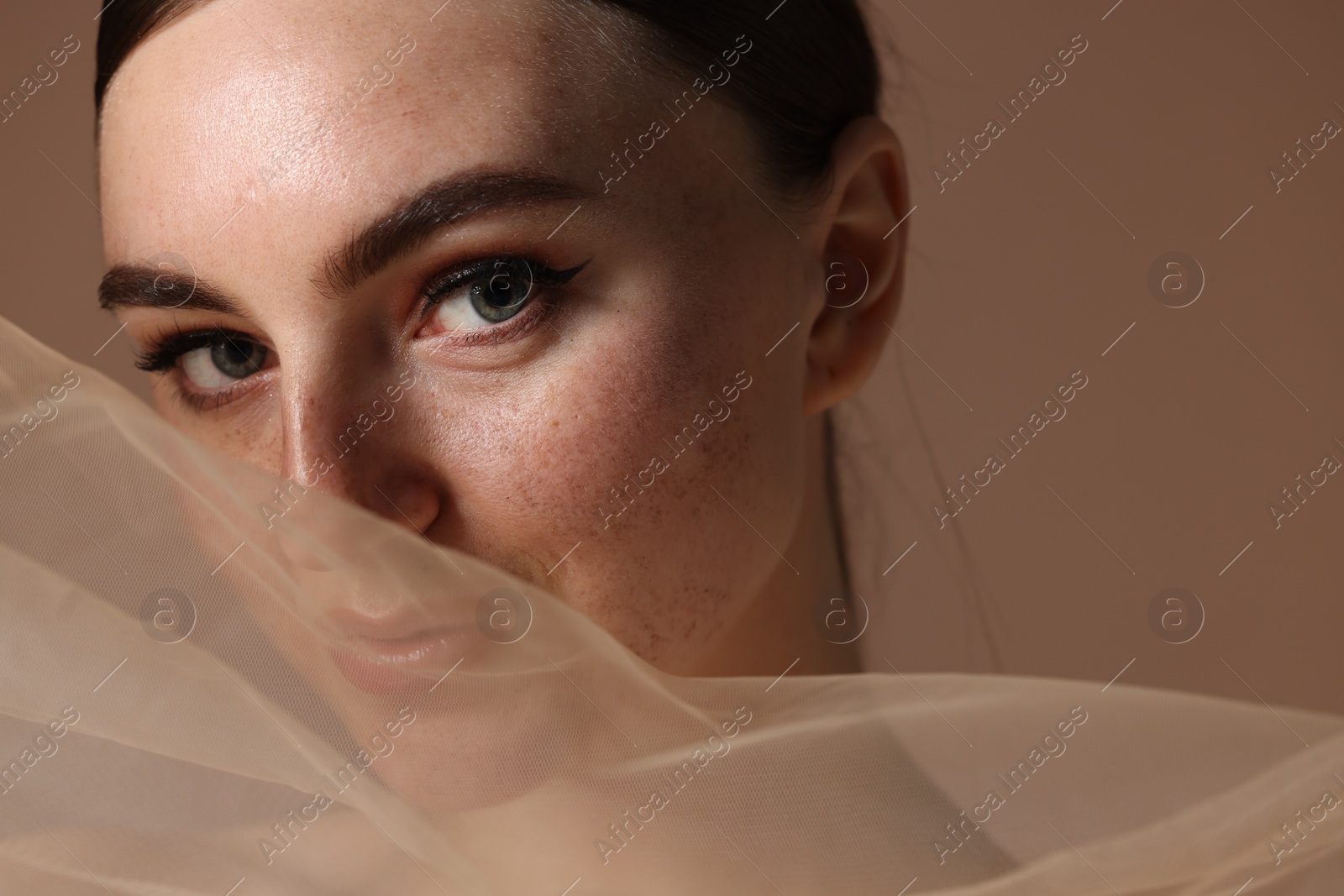 Photo of Fashionable portrait of beautiful woman with fake freckles on brown background, closeup