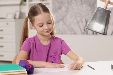 Photo of Girl using eraser at white desk in room