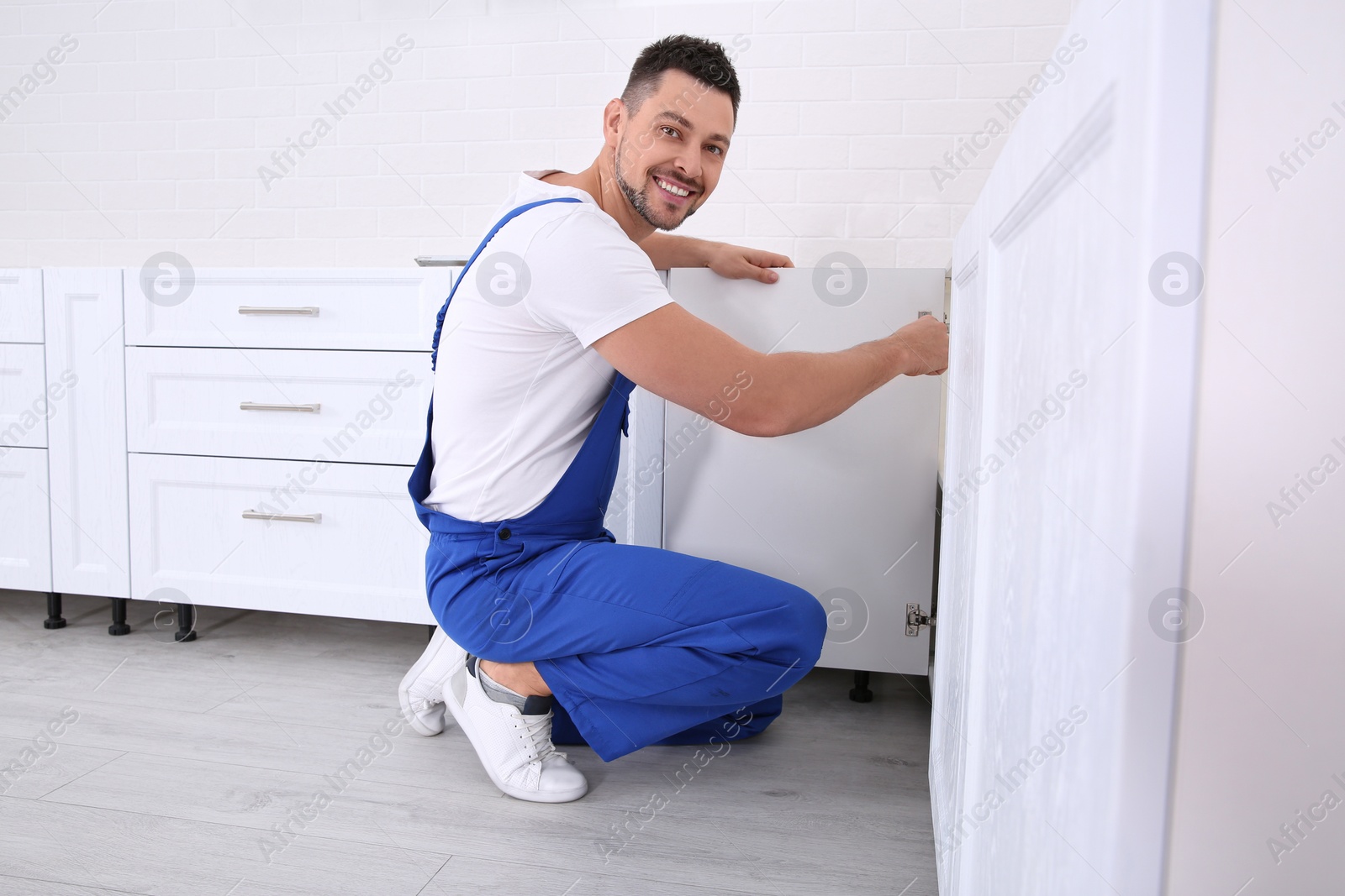 Photo of Worker installing door of cabinet in kitchen