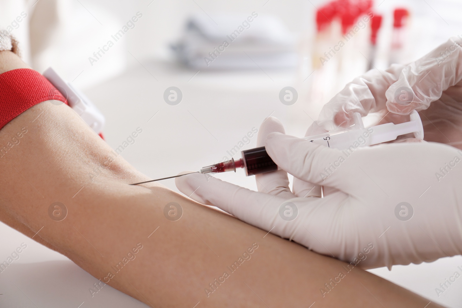 Photo of Nurse drawing blood sample from patient in clinic, closeup