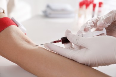 Nurse drawing blood sample from patient in clinic, closeup