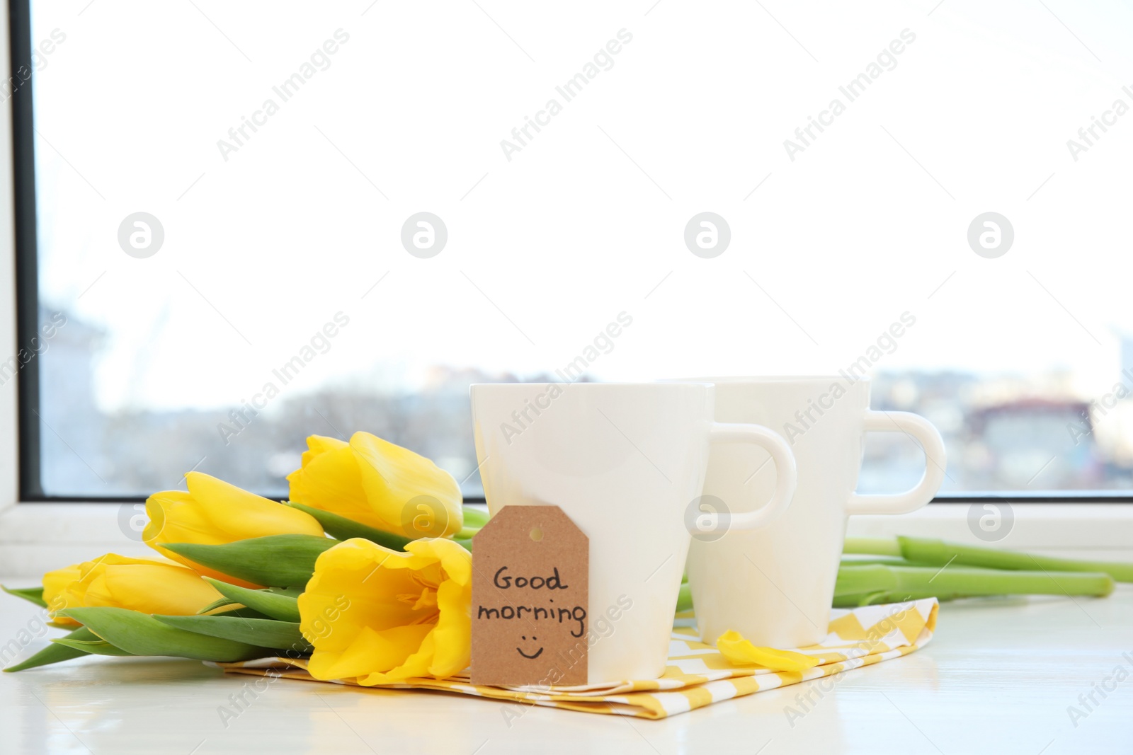 Photo of Aromatic coffee, beautiful flowers and GOOD MORNING wish on light windowsill