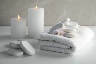 Photo of Spa stones, towel and burning candles on white table