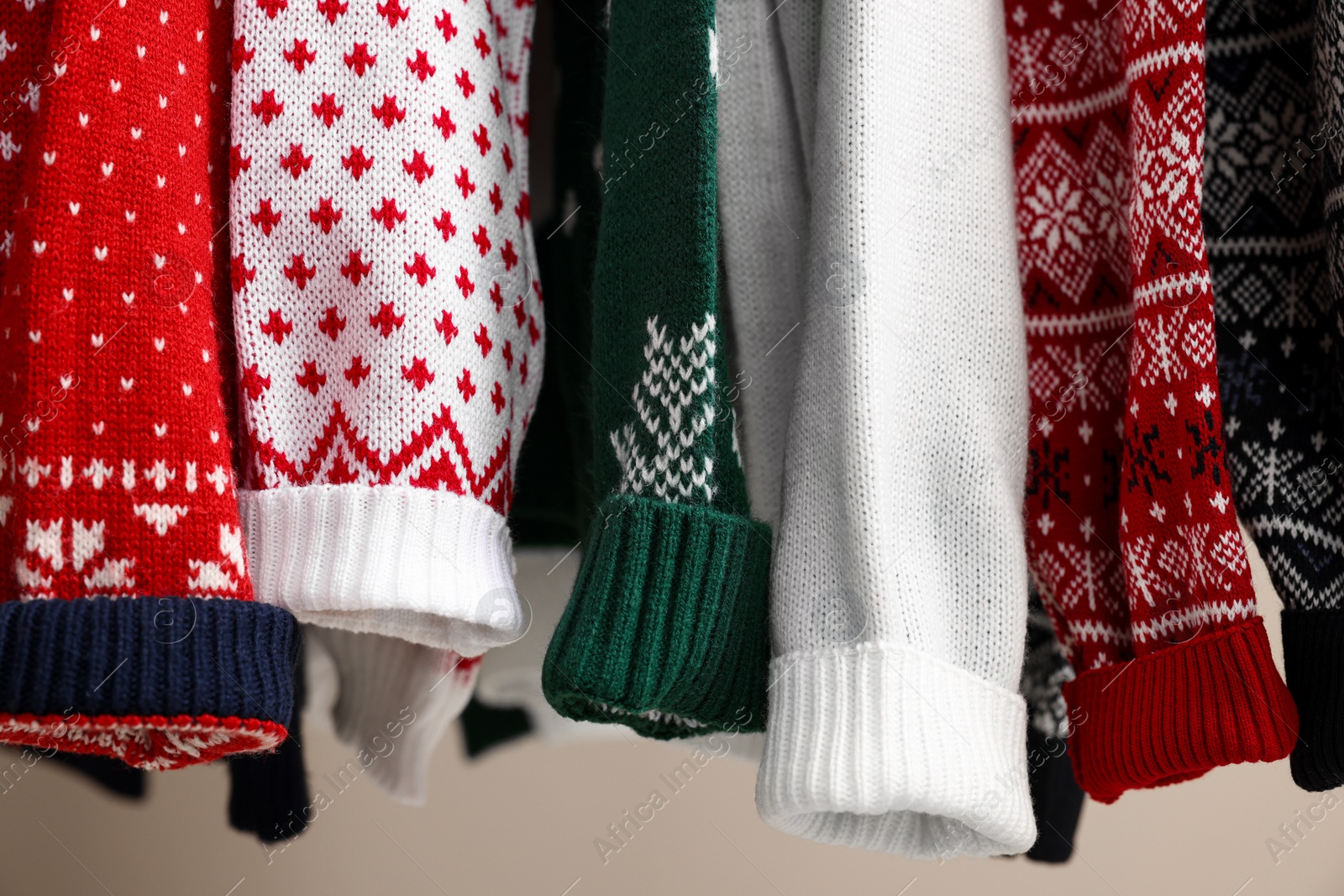 Photo of Different Christmas sweaters hanging on rack, closeup