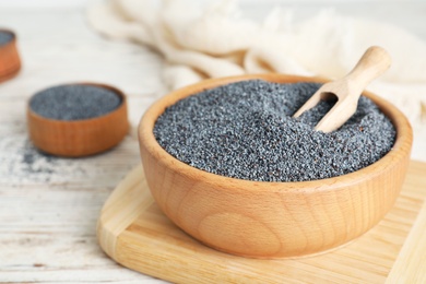 Photo of Poppy seeds in wooden dishware on table