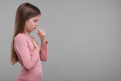 Photo of Sick girl coughing on gray background, space for text