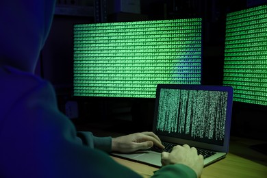 Photo of Hacker working with computers at wooden table, closeup. Cyber attack