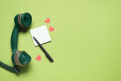 Photo of Long-distance relationship concept. Telephone receiver, empty note, paper hearts and pen on light green background, flat lay with space for text