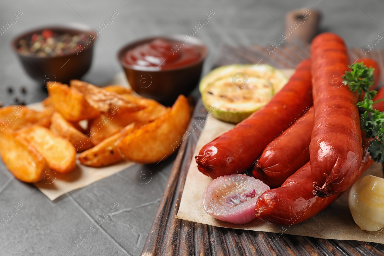 Photo of Delicious grilled sausages and vegetables on grey table, closeup. Space for text