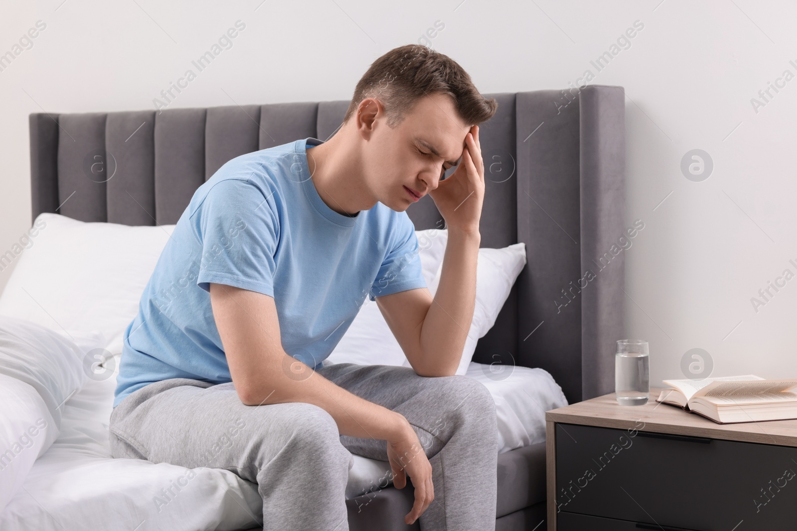 Photo of Sad man suffering from headache on bed indoors, space for text