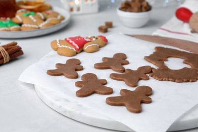 Photo of Making homemade Christmas cookies. Dough for gingerbread man and cutter on white table