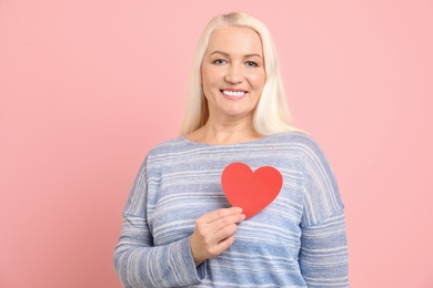 Photo of Portrait of mature woman with decorative paper heart on color background