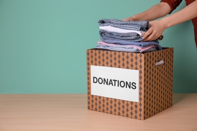 Female volunteer putting clothes into donation box on table