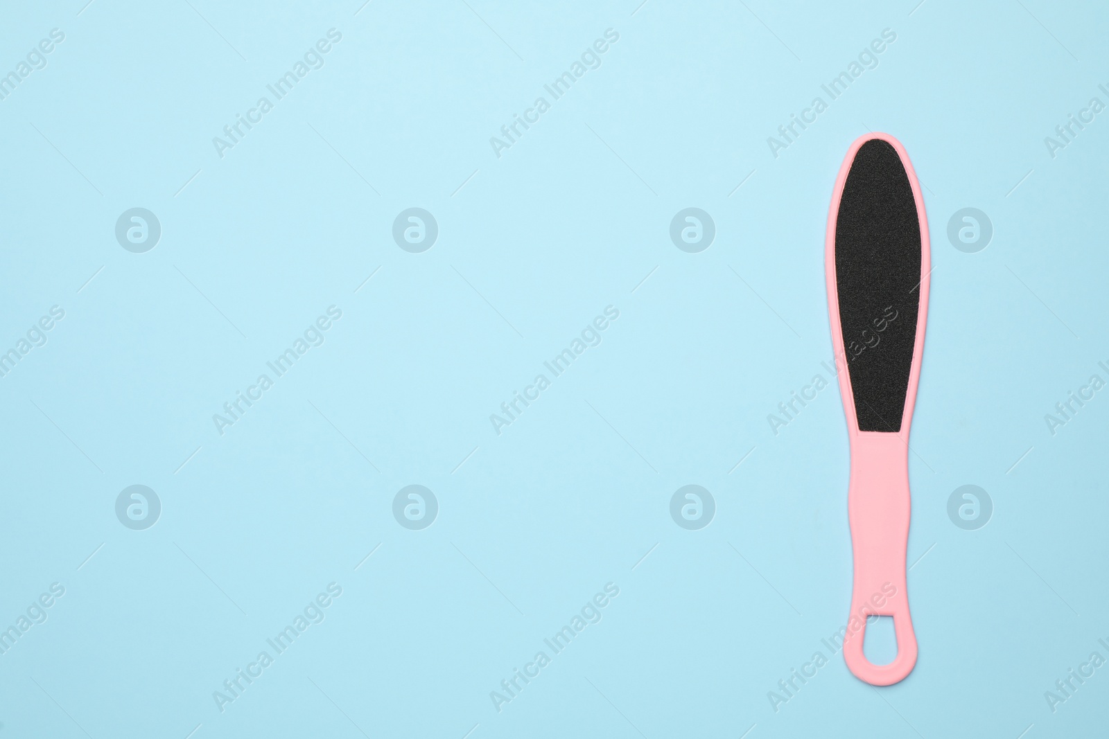 Photo of Pink foot file on light blue background, top view with space for text. Pedicure tool