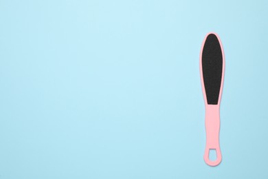 Photo of Pink foot file on light blue background, top view with space for text. Pedicure tool