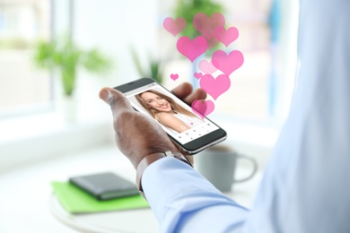 Image of African-American man visiting dating site via smartphone indoors, closeup
