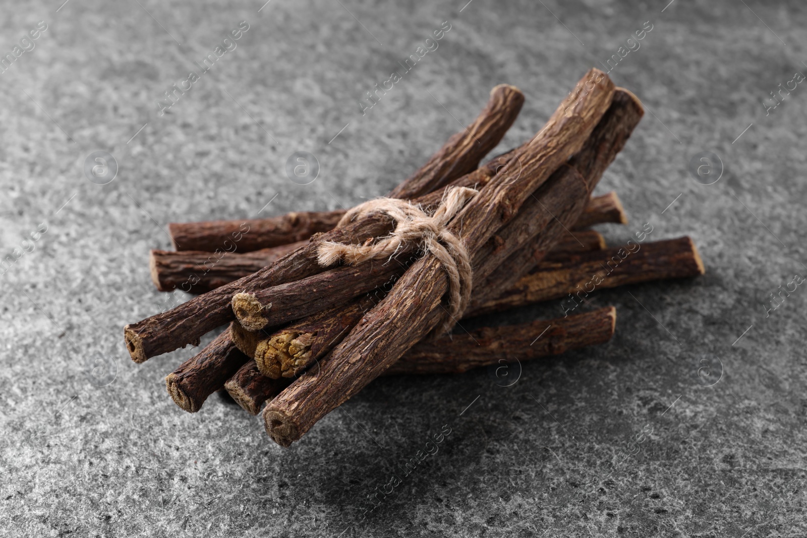 Photo of Dried sticks of liquorice root on grey table, closeup