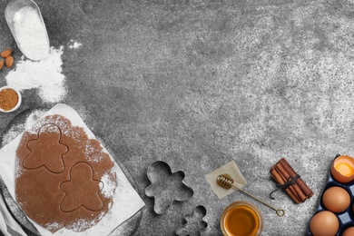 Flat lay composition with homemade gingerbread man cookies on grey table, space for text