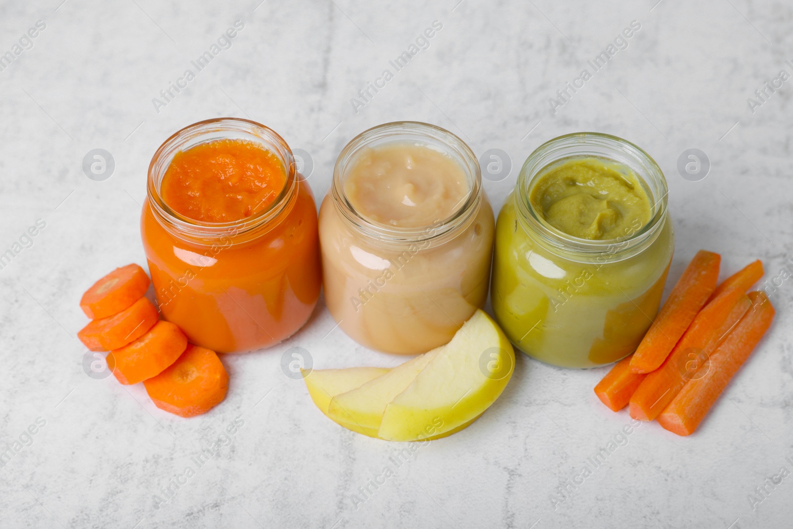 Photo of Jars with healthy baby food and ingredients on white textured table