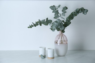Photo of Beautiful eucalyptus branches and candles on grey table, space for text. Interior element