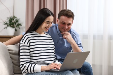 Photo of Happy couple using laptop together at home