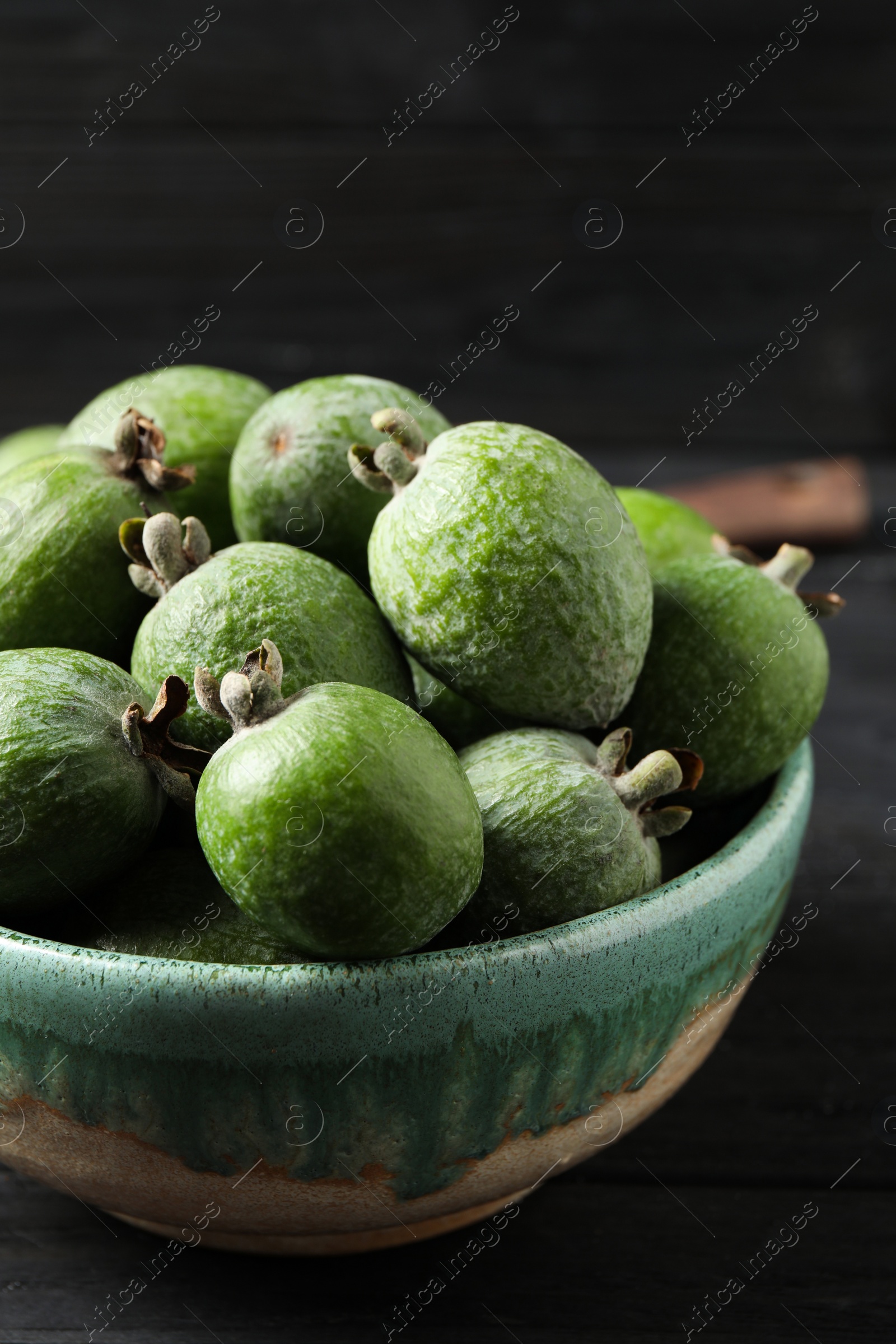 Photo of Fresh green feijoa fruits on black wooden table, closeup