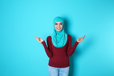 Photo of Portrait of young Muslim woman in hijab against color background