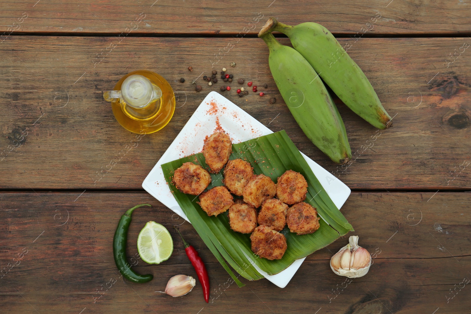 Photo of Delicious fried bananas, fresh fruits and different peppers on wooden table, flat lay